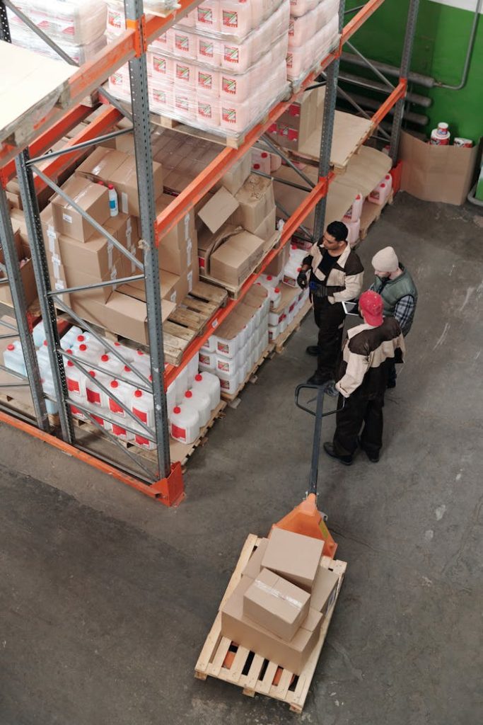 men-working-in-a-warehouse-4481258 Three warehouse workers discussing inventory organization details.