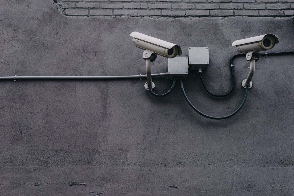 two-gray-bullet-security-cameras-430208 Two surveillance cameras mounted on a concrete wall, highlighting security technology.